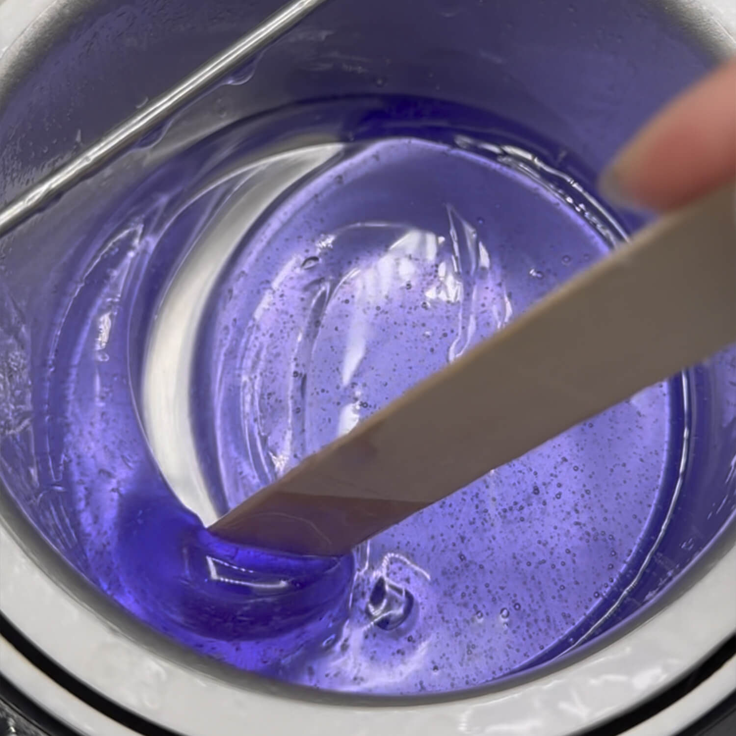 purple hair removal wax mixed with a wooden stick