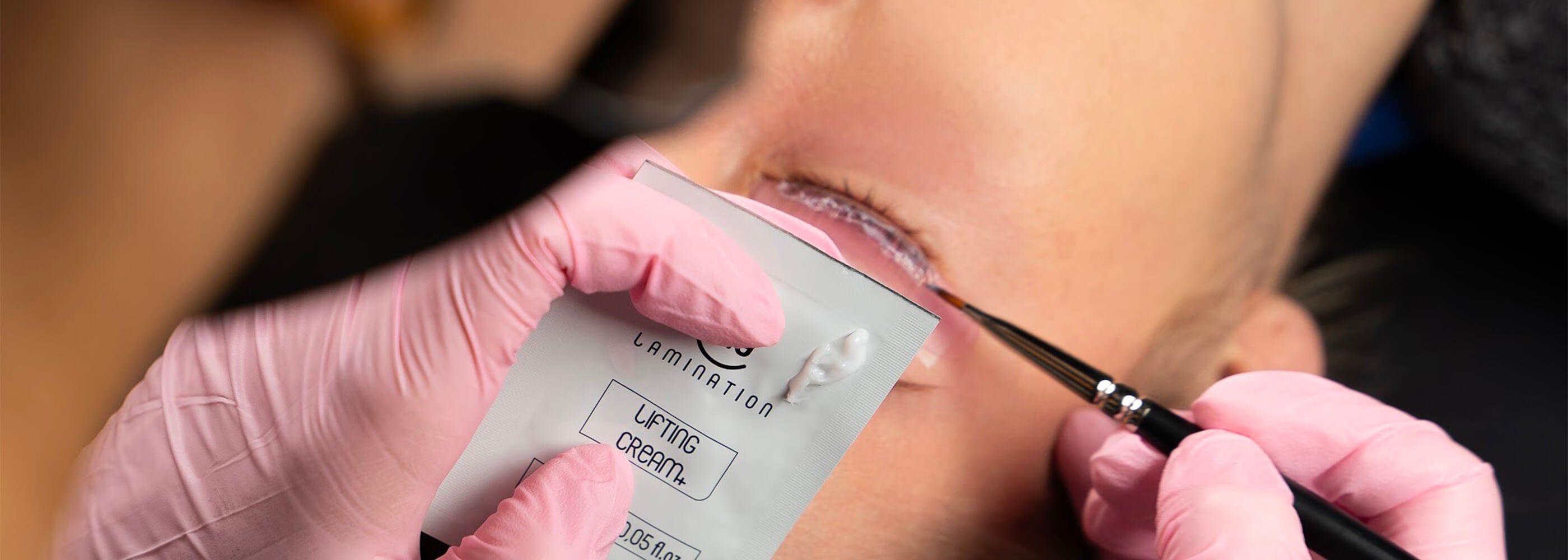 A beautician applies My Lamination Lifting Cream to a client's eyelashes