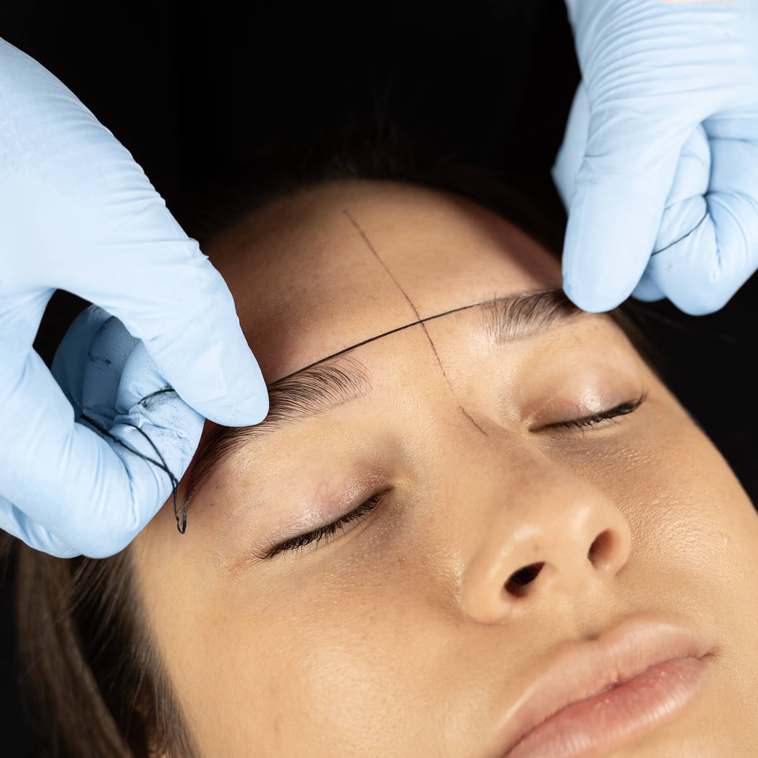 estetista appoggia il mapping brow per definire l'architettura sopraccigliare della cliente